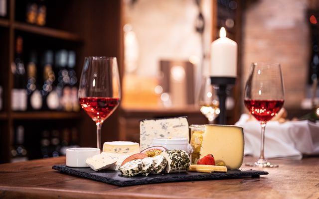 Ein Käsebrett mit 2 Gläsern Wein im Weinkeller des Hotels