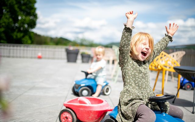 Kinder mit Bobbycars auf der Sonnenterrasse