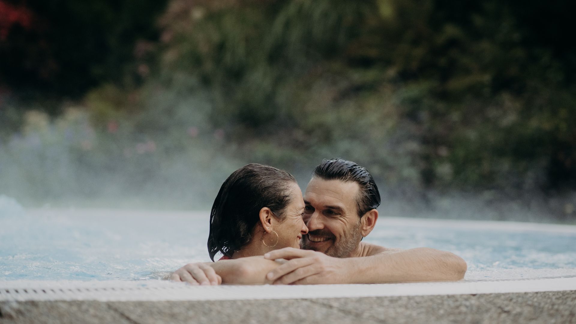 Paar im Außenpool des Hotel Sonngastein – Wellness, Entspannung und romantische Auszeit in Gastein.