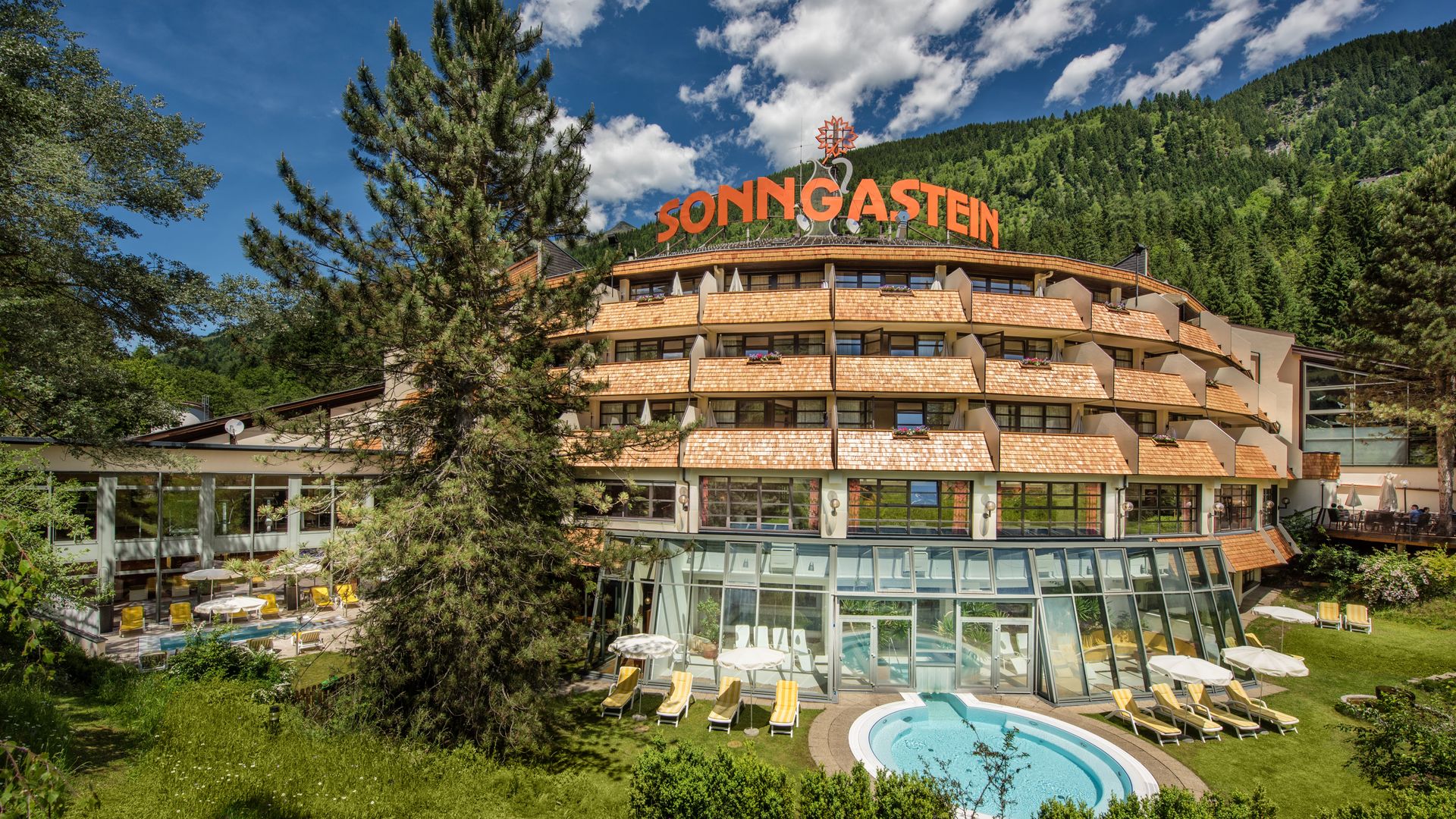 Sommeransicht vom Hotel Sonngastein mit Garten, Außenpool und Bergkulisse in Gastein.