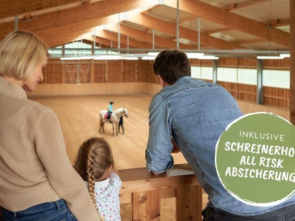 Familie schaut der Tochter beim Reiten zu in der großen Reithalle