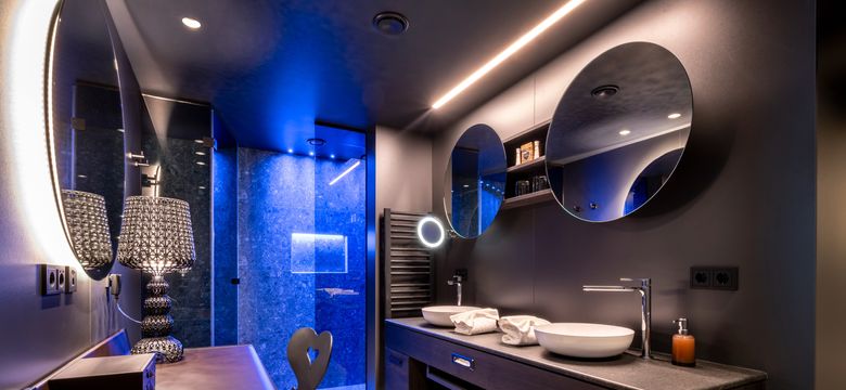 Wohlfühlzimmer "Heimatglück" mit großem Bad, zwei Waschbecken und Spiegel, Kosmetiktisch und Regendusche.