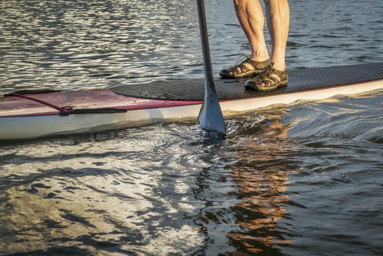Aufnahme von den Unterschenkeln eines Mannes, der im Rahmen seines Kurzurlaubes an der Ostsee Stand-Up Paddling betreibt