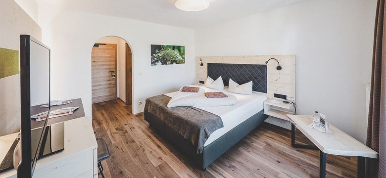 Zimmeransicht mit Boxspringbett und Durchgang zum Badezimmer