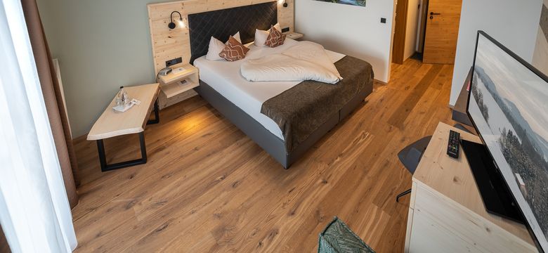 Zimmeransicht mit Boxspringbett, Bank und TV