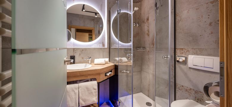 Moderne Bäder in grau gefliest mit rundem, beleuchteten Spiegel