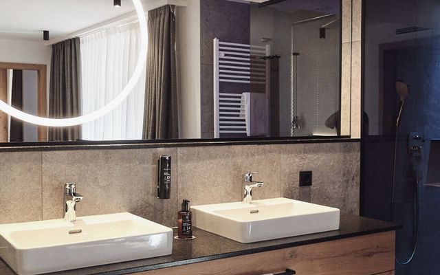 Das Badezimmer der HOCHKÖNIGIN vereint modernes Design mit luxuriösen Details: stilvolle Armaturen, klare Linien und eine harmonische Lichtinszenierung schaffen eine Atmosphäre von Ruhe und Eleganz.