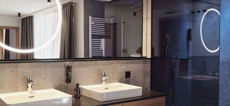 Das Badezimmer der HOCHKÖNIGIN vereint modernes Design mit luxuriösen Details: stilvolle Armaturen, klare Linien und eine harmonische Lichtinszenierung schaffen eine Atmosphäre von Ruhe und Eleganz.