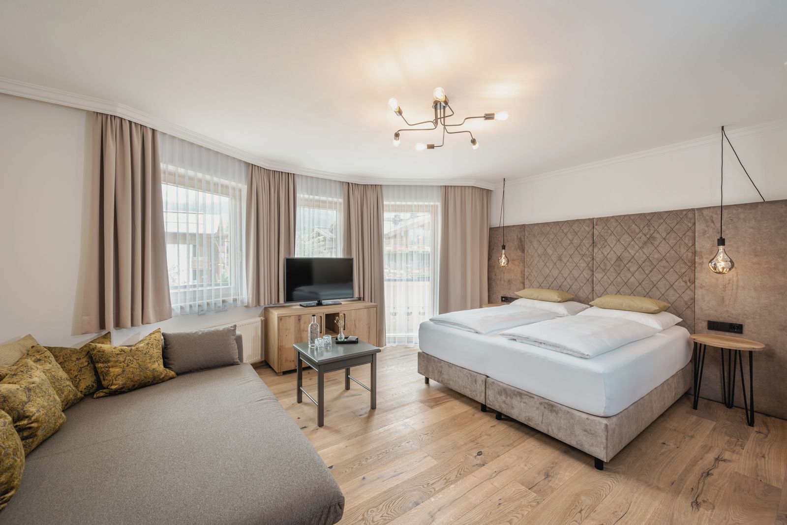 Zimmer im Hotel die HOCHKÖNIGIN mit Blick auf das Bett und Sofa und in den Raum hinein